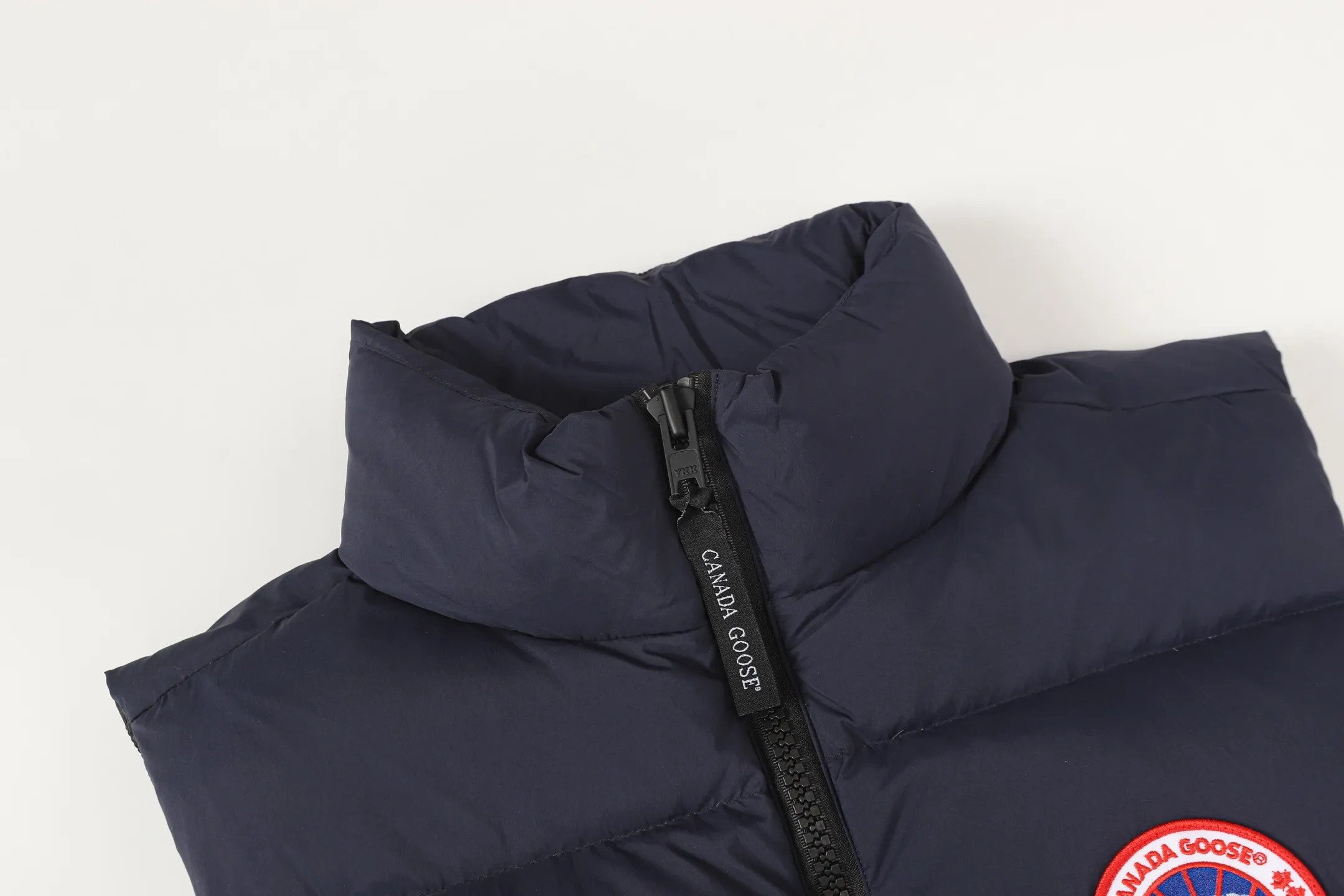 P560 Canada gooes Lawrence down vest (high version) The Lawrence down vest features a durable shell and quilted body, making it a must-have item for all seasons. The fabric has a durable soft touch. Longer hem at back for added protection. Reflective double-stripe grip tape at back. The Lawrence features an engineered down-filled collar to block strong winds, a two-way front zip and a longer rear hem.  Color: black with red label, black with black label, desert color, ocean blue Size: XS-2XL